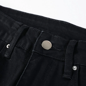 Close-up of black denim waist with silver metal button and reinforced stitching detail