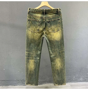 Detail view of back pockets on men's vintage yellow-green washed straight denim jeans