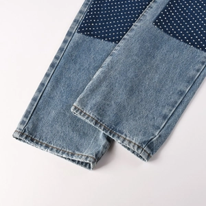 Detail of blue denim jeans featuring sparkling rhinestone patches and a retro washed finish