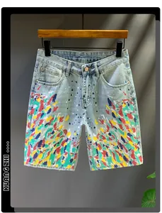 Close-up of light blue washed denim shorts featuring artistic colorful paint splatter details