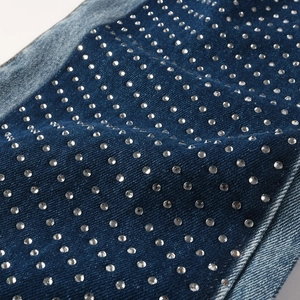 Macro detail of sparkling rhinestones on dark blue vintage straight-leg denim fabric