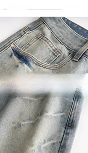 Detail of washed denim shorts showing vintage blue fabric and copper rivet reinforcement