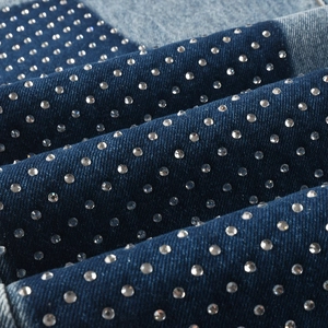 Detailed close-up of dark blue denim fabric with sparkling rhinestone embellishments