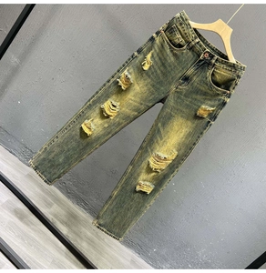 Detailed close-up of retro yellow acid wash denim texture and distressed ripped design