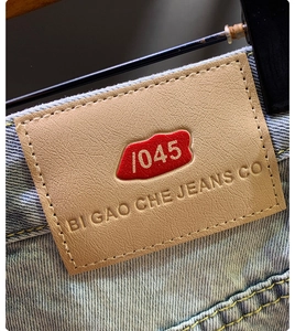 Close-up of brown leather waist label and premium stitching on light blue denim shorts