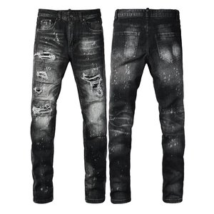 Close-up of black distressed jeans featuring white paint splatter and ripped details