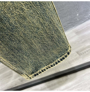 Detailed view of sulfur-washed heavy denim fabric with vintage distressed texture and seams