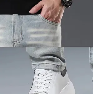 Detailed close-up of light blue distressed jeans with whiskers and stacked hem design