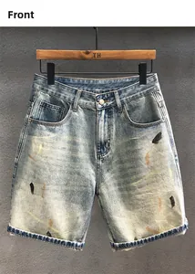 Close-up of vintage washed denim shorts featuring artistic paint splatters and cuffed hems