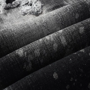 Macro shot of distressed denim fabric featuring vintage ripped holes and faded whiskers