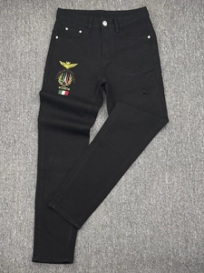 Close-up of golden eagle embroidery and distressed details on black slim denim jeans