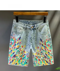Detail of light blue denim shorts featuring artistic colorful paint splatter design