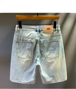 Detail view of back pockets and leather waist patch on light blue washed denim shorts