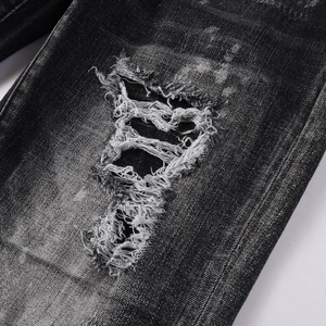 Macro detail of distressed dark grey denim with frayed holes and washed texture