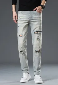 Detailed close-up of light blue slim fit jeans with red plaid patch and distressed ripped detail