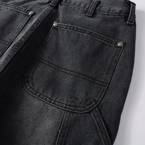 Detailed view of rear pocket on vintage black denim pants with metal rivet accents