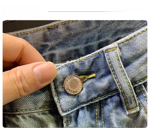 Detail view of the metal button and contrast stitching on washed blue denim shorts
