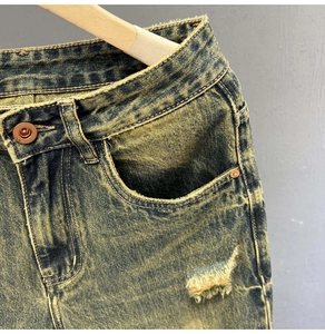 Detailed macro view of vintage light wash denim jeans with distressed holes and brass button