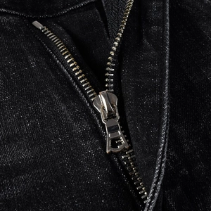 Close-up of black denim jeans with metallic zipper and shimmering textured fabric