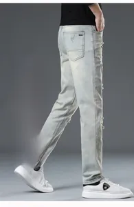 Detail view of light blue distressed denim jeans with ripped holes and retro wash finish
