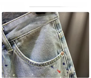 Close-up of light blue denim shorts with asymmetric waist design and colorful paint splatter