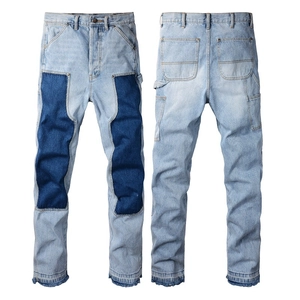 Detail view showing light blue denim pants with dark contrast patchwork and utility hammer loop