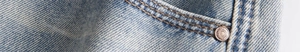 Detailed macro view of denim fabric texture with orange double stitching and metal rivet