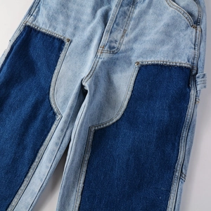 Detail view of vintage patchwork denim jeans with contrast fabric and metallic rivets