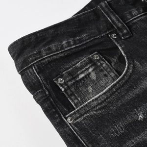 Close-up of the waist and pocket details on black washed distressed denim jeans