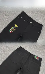 Detail view of the embroidered eagle shield emblem and leather waist patch on men's slim jeans
