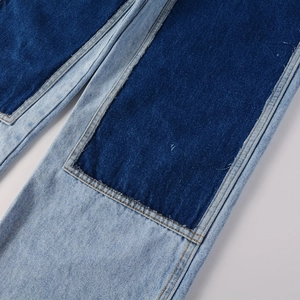 Detailed close-up of blue patchwork denim fabric and high-quality stitching on jeans