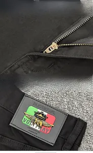 Detail view of premium black denim pants showing YKK zipper and leather brand patch