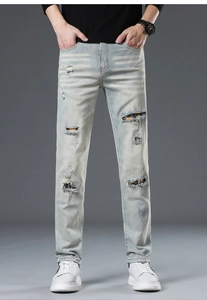 Detail of light blue ripped jeans with orange and blue plaid lining inside the distressed holes