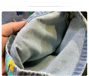 Detail of washed denim shorts featuring colorful graffiti print and frayed hem edges