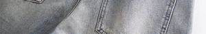 Close-up of light blue washed denim fabric showing twill weave and stitching details