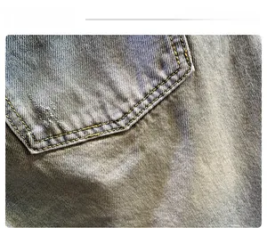 Detailed macro view of blue washed denim shorts featuring yellow contrast stitching