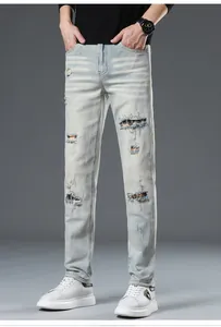 Detail of light blue ripped jeans showing multi-color plaid fabric patches inside the holes