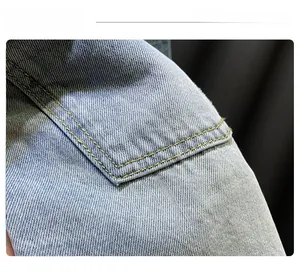 Detailed macro view of light blue denim fabric with reinforced double yellow stitching