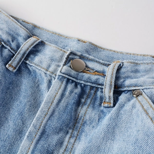Close-up of vintage blue denim jeans featuring metal button, rivets, and yellow stitching