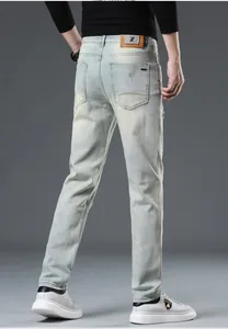 Detailed back view of men's slim fit light blue washed denim jeans with leather waist patch