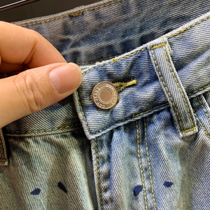 Light blue washed denim shorts featuring metal button detail and paint splatter effect