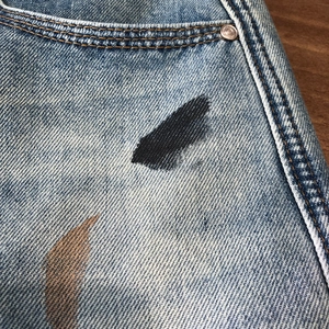 Vintage wash blue denim shorts for men featuring graffiti stains and metal rivets