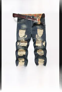Detail of ripped jeans with distressed patches, frayed hems and orange plaid lining