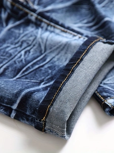 Gros plan détaillé du denim délavé marbré bleu avec coutures jaunes contrastantes