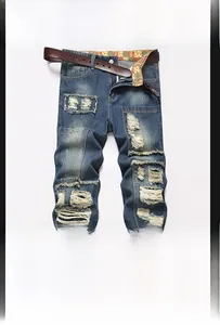 Detail of vintage ripped jeans with distressed holes and a classic brown leather belt