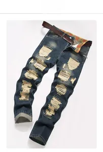 Close-up of distressed blue denim jeans with ripped holes and colorful plaid waistband lining