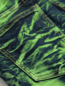 Détail du tissu en denim tie-dye vert néon et noir sur la poche arrière du jean pour homme