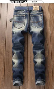 Detail of vintage washed blue jeans back pockets with red V-shaped stitching and leather tag