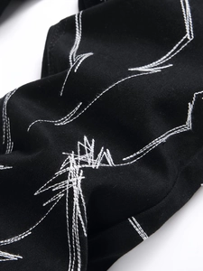 Détail d'un jean stretch noir avec broderie géométrique contrastée blanche de haute qualité