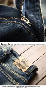 Detailed macro view of dark blue washed denim with leather patch and copper zipper